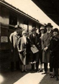 Plano general de Filip Lajar, una mujer, Arthur Rubinstein, una mujer, un hombre y una mujer posando delante de un tren