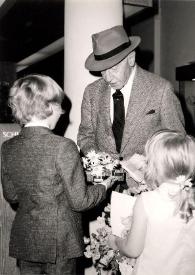 Plano medio de Arthur Rubinstein recibiendo un obsequio de manos de dos niños