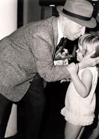Plano medio de Arthur Rubinstein besando a una niña que le ha entregado un obsequio