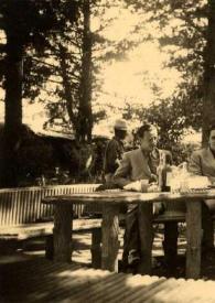 Plano medio de dos hombres, Arthur Rubinstein, Aniela Rubinstein, una mujer y un niño sentados en una mesa en el campo, posando