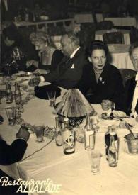 Plano medio de Aniela Rubinstein y Arthur Rubinstein sentados en la mesa junto con otras personas posando