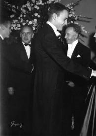 Plano general de Eva Rubinstein estrechando la mano a un hombre. Detrás, Arthur Rubinstein y Aniela Rubinstein saludando a dos hombres