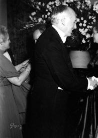 Plano general de Eva Rubinstein estrechando la mano a un señor y Arthur Rubinstein a una señora, mientras Aniela Rubinstein observándoles