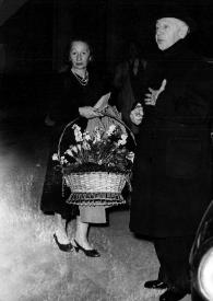 Plano general de Arthur Rubinstein saliendo de un coche. Junto a él una señora con un cesto de flores