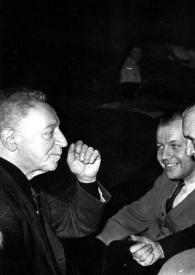Plano medio de Arthur Rubinstein (perfil derecho) charlando con Jerzy Katlewicz  y otro hombre