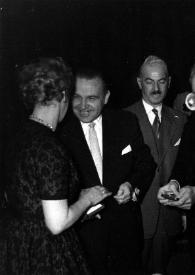 Plano medio de Arthur Rubinstein, con la condecoración en la mano, entrevistado por un periodista, en presencia del Alcalde de Lodz y de Aniela Rubinstein