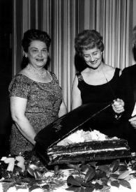 Plano general de Arthur Rubinstein con un cuchillo, delante de una tarta en forma de piano. A su lado, Aniela Rubinstein, la Señora de. Harry E. Callaway y el Harry E. Callaway posando