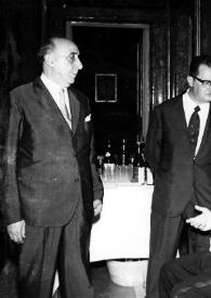 Plano general de Arthur Rubinstein (perfil izquierdo), sentado, conversando con tres hombres