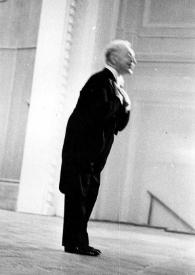 Plano general de Arthur Rubinstein (perfil derecho) de pie, en el escenario, saludando al público