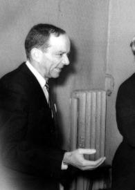 Plano general de un hombre observando a una mujer saludar a Arthur Rubinstein (perfil izquierdo), detrás Sol Hurok les observa