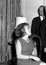 Plano general de una mujer sentada charlando con Arthur Rubinstein, detrás un hombre les observa