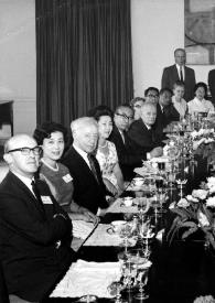 Plano general de Arthur Rubinstein, sentado a la mesa junto a más personas