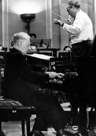 Plano medio de Arthur Rubinstein (perfil derecho) sentado al piano delante de János Ferencsik dirigiendo la orquesta