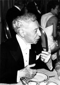 Plano medio de Arthur Rubinstein (perfil derecho) y Helen H. Hull (perfil izquierdo) charlando sentados en una mesa