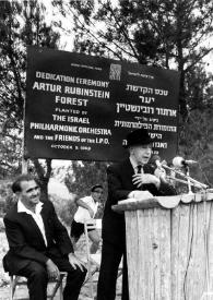 Plano general de Arthur Rubinstein hablando en el atril mientras el Señor Barzilai (Ministro de Sanidad Pública de Israel) le observa sentado detrás