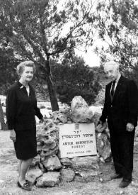 Plano general de Aniela Rubinstein (medio perfil derecho) y Arthur Rubinstein (medio perfil izquierdo) posando con la placa conmemorativa entre ellos dos