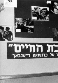 Plano medio de Aniela Rubinstein posando con un ramo de flores en la mano delante de un cartel con fotos de Arthur Rubinstein