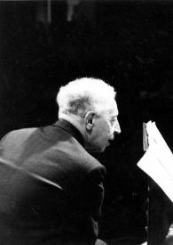 Plano medio de Arthur Rubinstein (medio perfil derecho) y Marta Argerich (medio perfil izquierdo) charlando sentados con una partitura en un atril entre ambos
