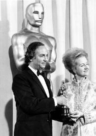 Plano medio de François Reichenbach y Aniela Rubinstein sujetando una estatuilla de los Premios Óscar, posando delante de una gran estatua Óscar. Óscar a Arthur Rubinstein por lel documental 
