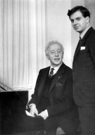 Plano general de Arthur Rubinstein sentado al piano y un hombre detrás de pie posando