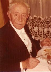 Plano medio de Arthur Rubinstein (medio perfil derecho) posando sentado en una mesa frente al plato de comida.