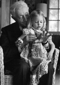 Plano general de Arthur Rubinstein sujetando en sus rodillas a Jessica Rubinstein mientras le enseña su mano, posando