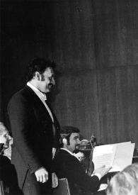 Plano medio de Zubin Mehta (perfil derecho) observando a Arthur Rubinstein (perfil derecho) junto a la orquesta, en el escenario
