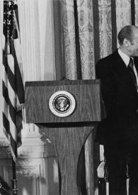 Plano general de Gerald Ford, Presidente de Estados Unidos, detrás del atril presidencial estrechando la mano a Arthur Rubinstein, detrás Betty Ford sentada aplaudiendo