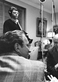 Plano medio de Arthur Rubinstein sentado en un sillón rodeado del equipo de televisión charlando, al fondo un cámara