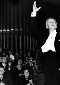 Plano general de Arthur Rubinstein saludando en el escenario, con un brazo en alto, detrás el público aplaudiendo