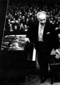 Plano general de Arthur Rubinstein levantándose del piano, al fondo el público aplaudiendo