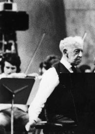 Plano medio de Arthur Rubinstein sentado al piano, detrás la orquesta