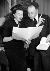 Plano general de una actriz y Arthur Rubinstein observando una gran hoja que la mujer sujeta en sus manos