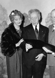 Plano general de Aniela Rubinstein, Arthur Rubinstein, un hombre y Helen H. Hull mirando una carpeta negra que sujetan Arthur y el hombre