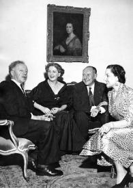 Plano general de Arthur Rubinstein y tres personas más sentados posando y charlando