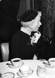 Plano medio de una mujer (perfil derecho) y Arthur Rubinstein (perfil izquierdo) sentados en una mesa charlando