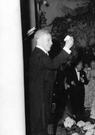 Plano general de Arthur Rubinstein (perfil derecho) saludando al público desde el escenario. Entre el público: Katherine Cardwell y Aniela Rubinstein