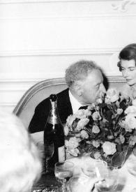 Plano medio de Arthur Rubinstein (perfil derecho) charlando con dos mujeres sentados en una mesa