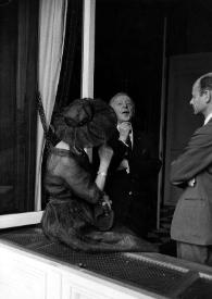 Plano medio de una mujer sentada de espaldas y de Arthur Rubinstein y un hombre charlando
