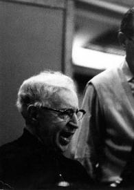 Plano medio de Arthur Rubinstein y Alfred Wallenstein charlando mientras observan un libreto de partituras situado en el piano en el que Arthur está sentado