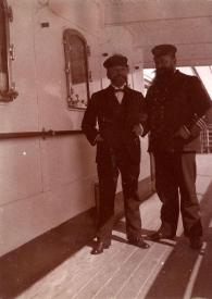 Plano general de un marinero y un oficial posando en la cubierta del barco