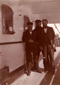 Plano general de un marinero, un oficial y un hombre posando en la cubierta del barco