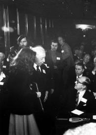 Plano medio de Arthur Rubinstein (perfil derecho) hablando con otros asistentes a la conferencia