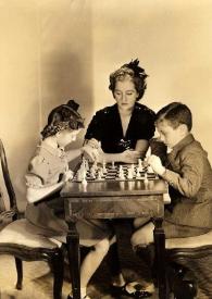 Plano general de Eva Rubinstein y Paul Rubinstein jugando al ajedrez mientras Aniela Rubinstein les observa