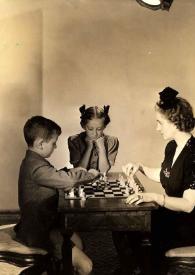 Plano general de Paul Rubinstein y Aniela Rubinstein jugando al ajedrez mientras Eva Rubinstein les observa