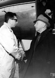 Plano medio de un hombre saludando a Arthur Rubinstein (perfil izquierdo) junto a un avión