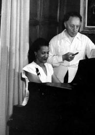 Portada:Plano medio de una mujer sentada al piano y Arthur Rubinstein observándola