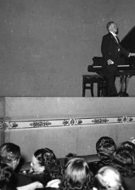 Portada:Plano general de Arthur Rubinstein (perfil derecho) de pie junto al piano, saludando al público