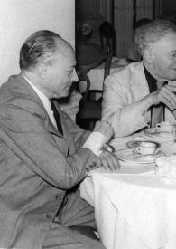 Portada:Plano medio de Arthur Rubinstein, fumando un puro rodeado por otras personas, sentados todos en una mesa