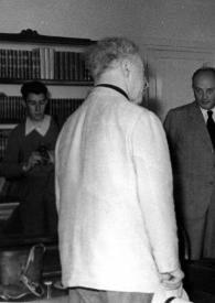 Portada:Plano general de Arthur Rubinstein (de espaldas) rodeado por otras personas, hablando con una mujer
